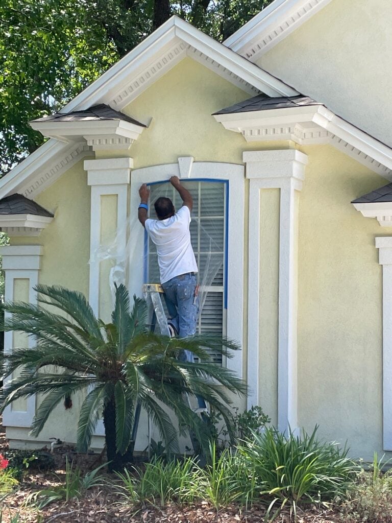 worker taping window cover during painting process