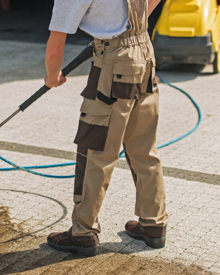 man scrubbing pavers with yellow cleaning tool in background