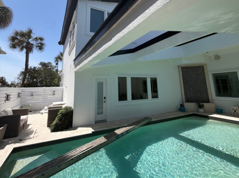 freshly painted white exterior of a ponte vedra beach property with a swimming pool and the backside of the home