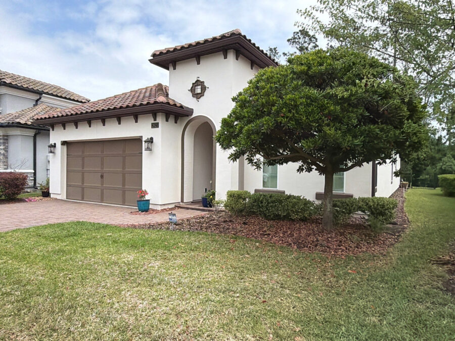 exterior of spanish style home with white stucco and brown accents on garage door and trim