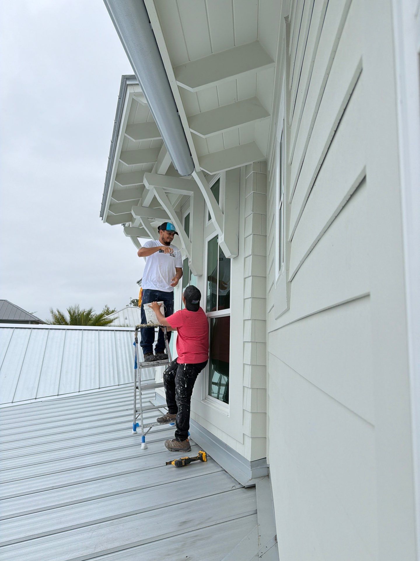 progress image on the exterior of a home with two bright side employees painting wood beams