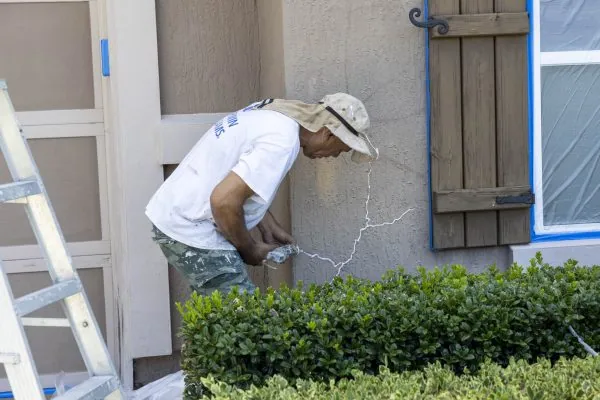 A man on the Bright Side Painting team doing stucco repair to an exterior project