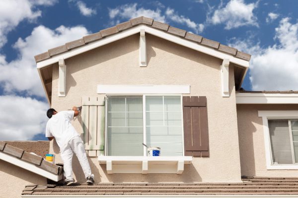 Professional House Painter Painting the Trim And Shutters of A Home.