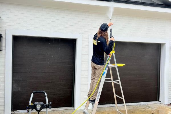 man on ladder pressure washing garage