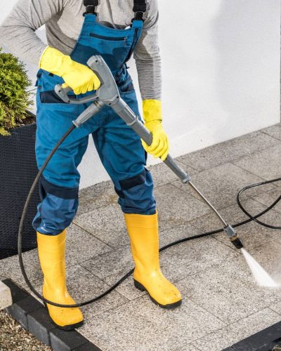 pressure-washing-outdoor-pavers-in-yellow-boots
