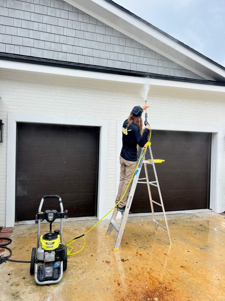 man on ladder pressure washing garage