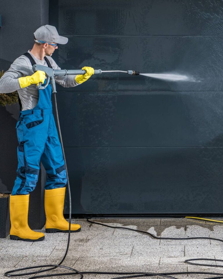man pressure washing driveway area